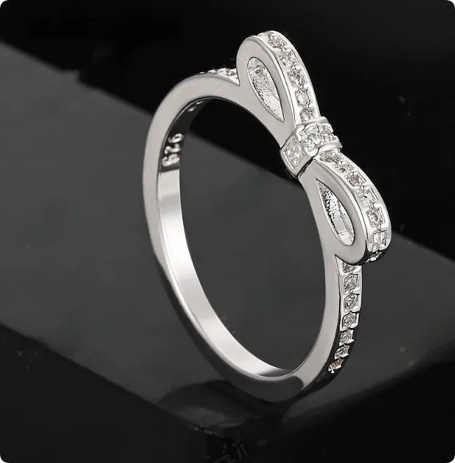 Silver bow-shaped ring with rhinestone detailing, shown in electroplated finish