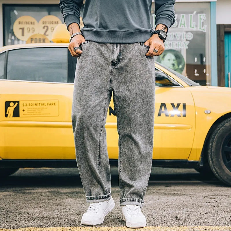Man wearing dark blue loose straight leg cotton jeans with a mid waist and zipper fly.