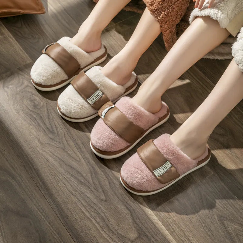 Women's beige plush slipper with Velcro strap and non-slip plastic sole on a wooden floor.