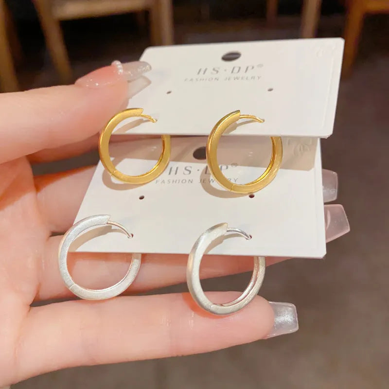 A pair of geometric round eyelet ear clips for women in gold or silver plating.