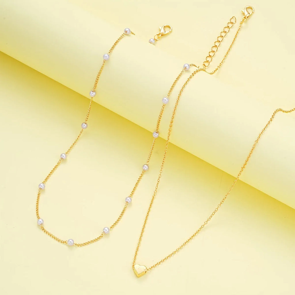 Double-layer stacked gold pearl heart necklace and bracelet jewelry set on display