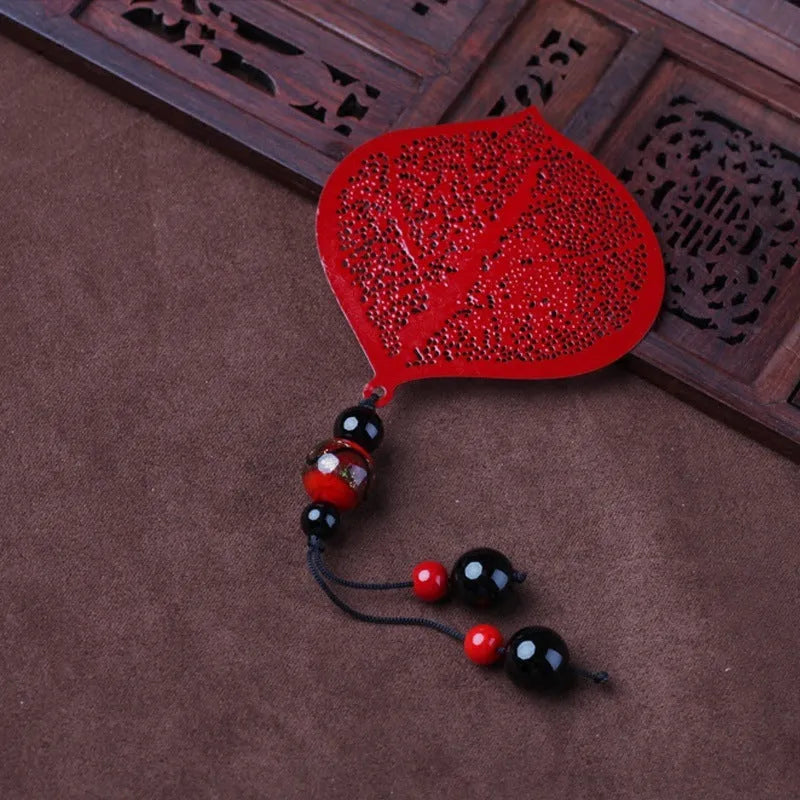 Brass metal bookmark with hollow leaf design and rose gold tassel in a presentation box.