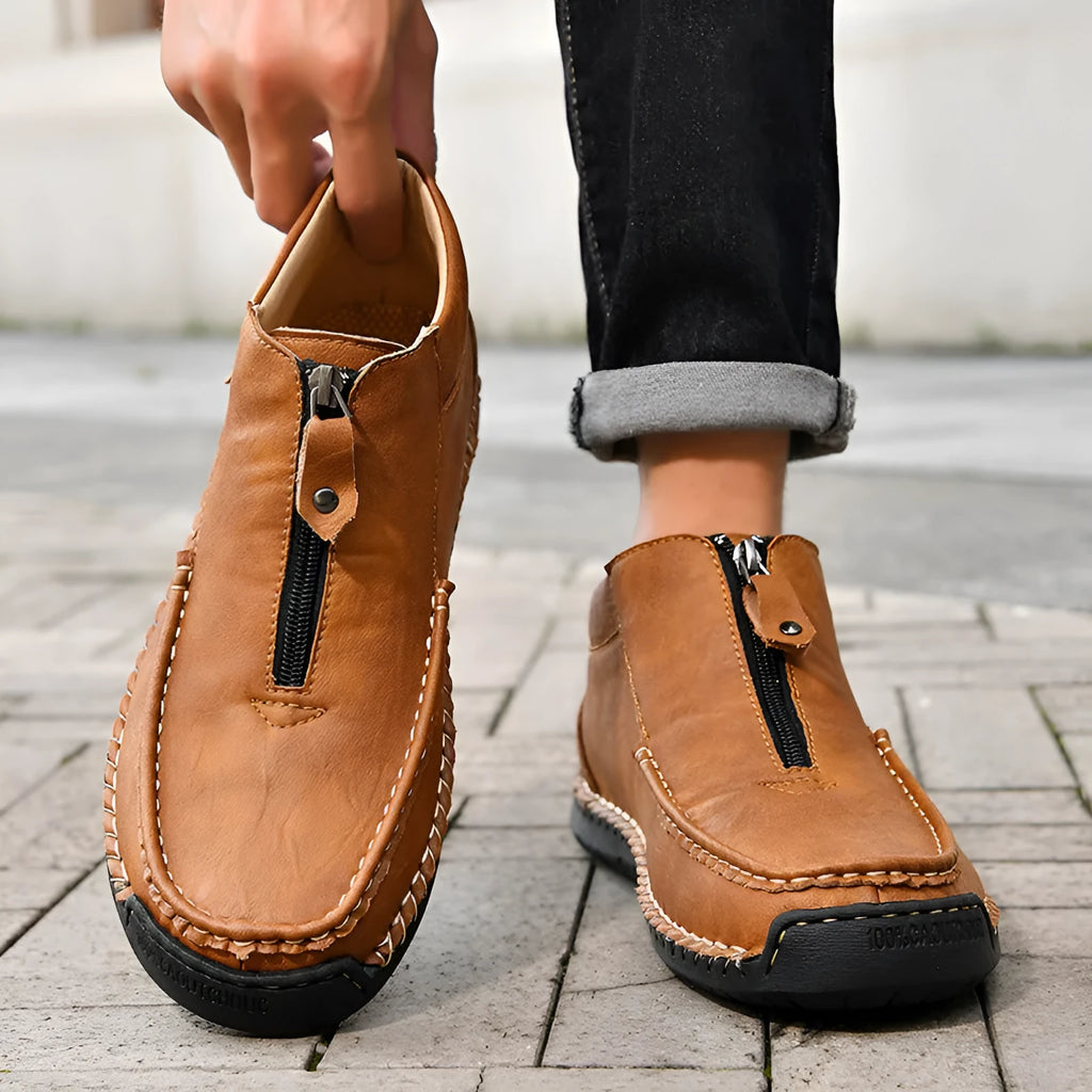 Men's black slip-on leather loafers with a round toe and rubber sole on a plain background.