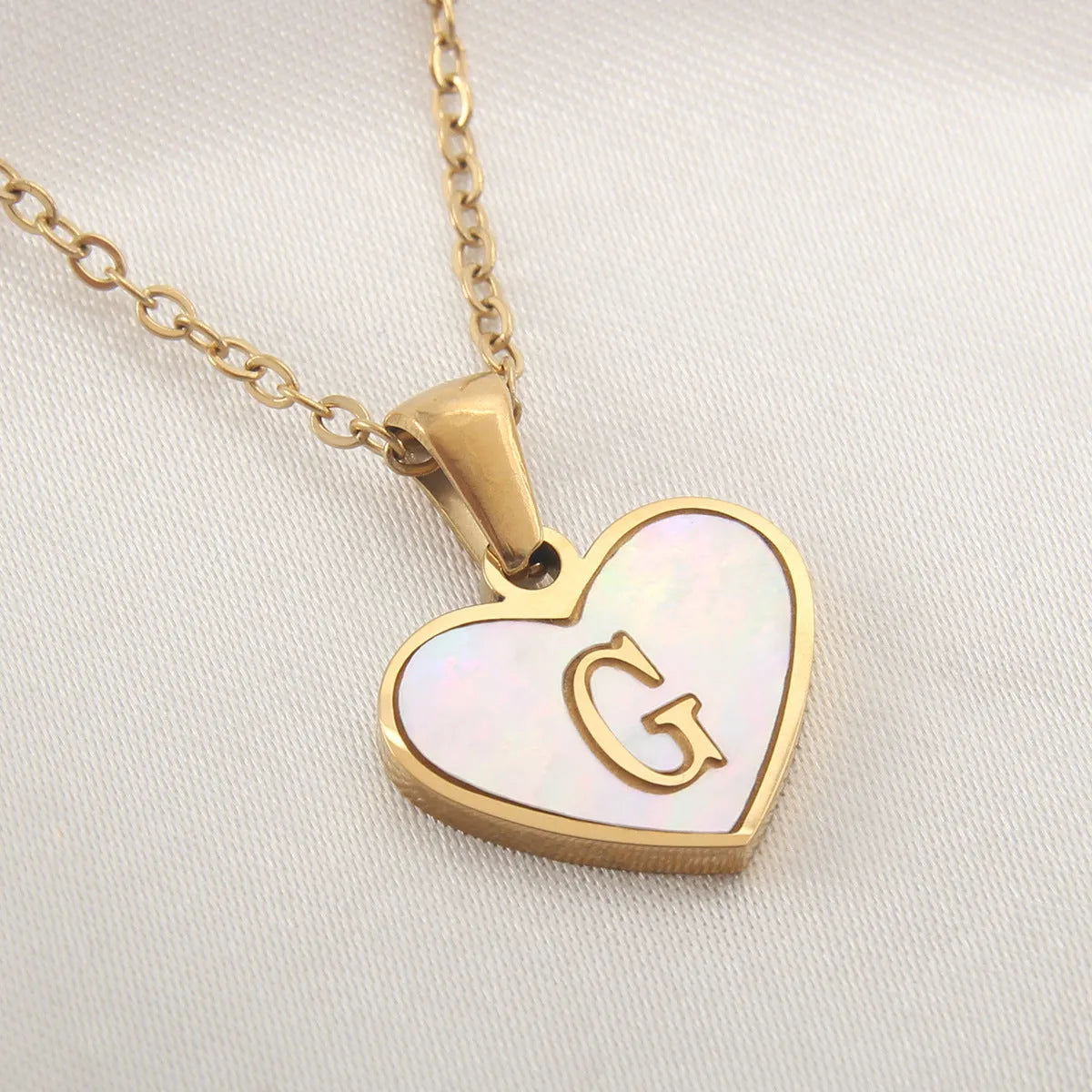 Gold plated heart-shaped necklace with a personalised initial letter and white shell detail on a 50cm adjustable chain.