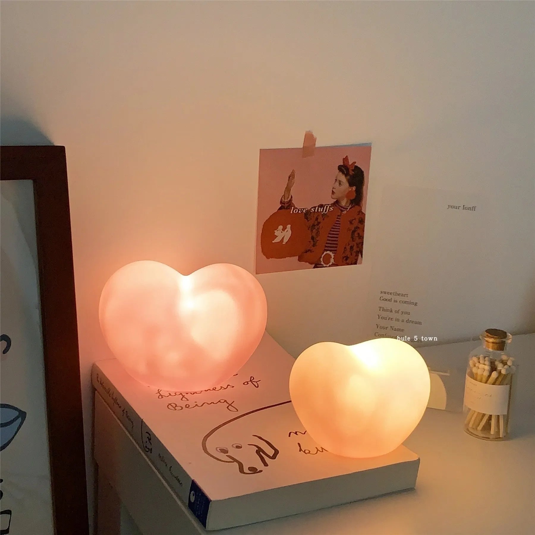 Small pink vinyl atmosphere lamp glowing with warm light on a wooden surface.