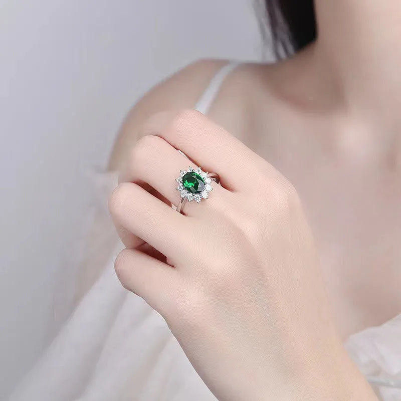 Women's copper floral ring with inlaid zirconium stones in green, blue, or red on a hand.