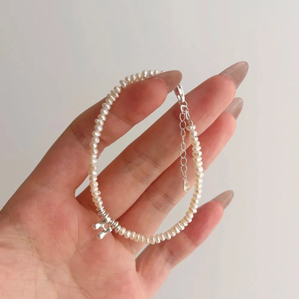 Women's natural freshwater pearl bracelet in 925 silver with letter shape charm on neutral background