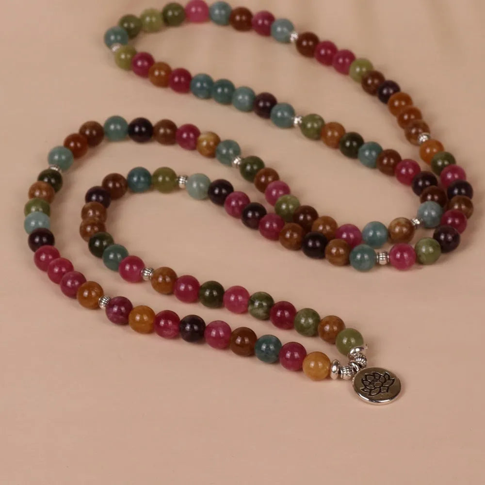 Close-up of a multi-layer beaded bracelet with 108 alloy beads and a central lotus pendant in a tourmaline colour.
