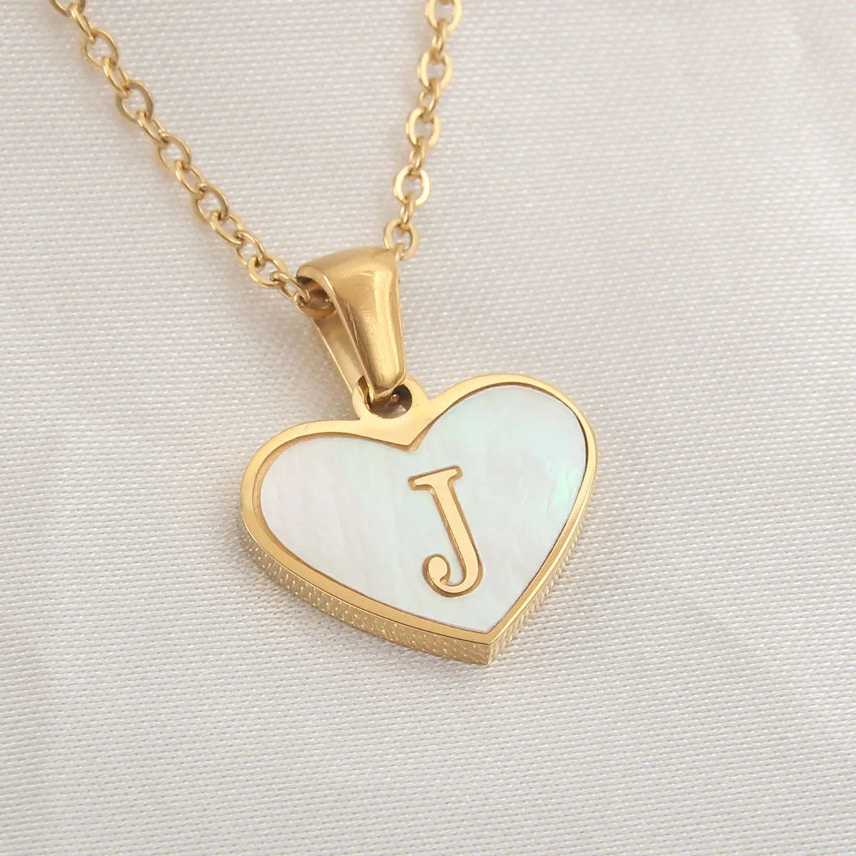 Gold plated heart-shaped necklace with a personalised initial letter and white shell detail on a 50cm adjustable chain.