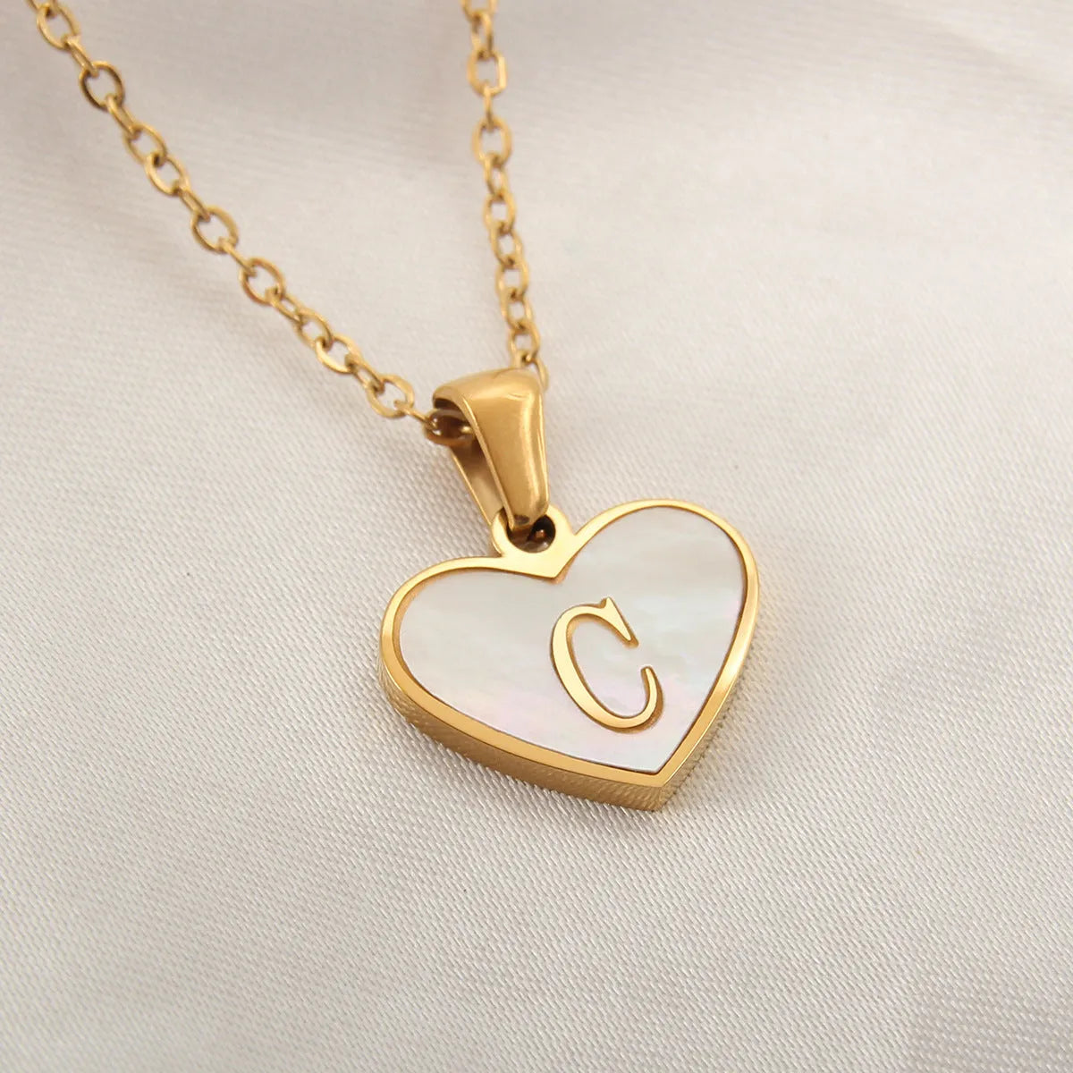 Gold plated heart-shaped necklace with a personalised initial letter and white shell detail on a 50cm adjustable chain.