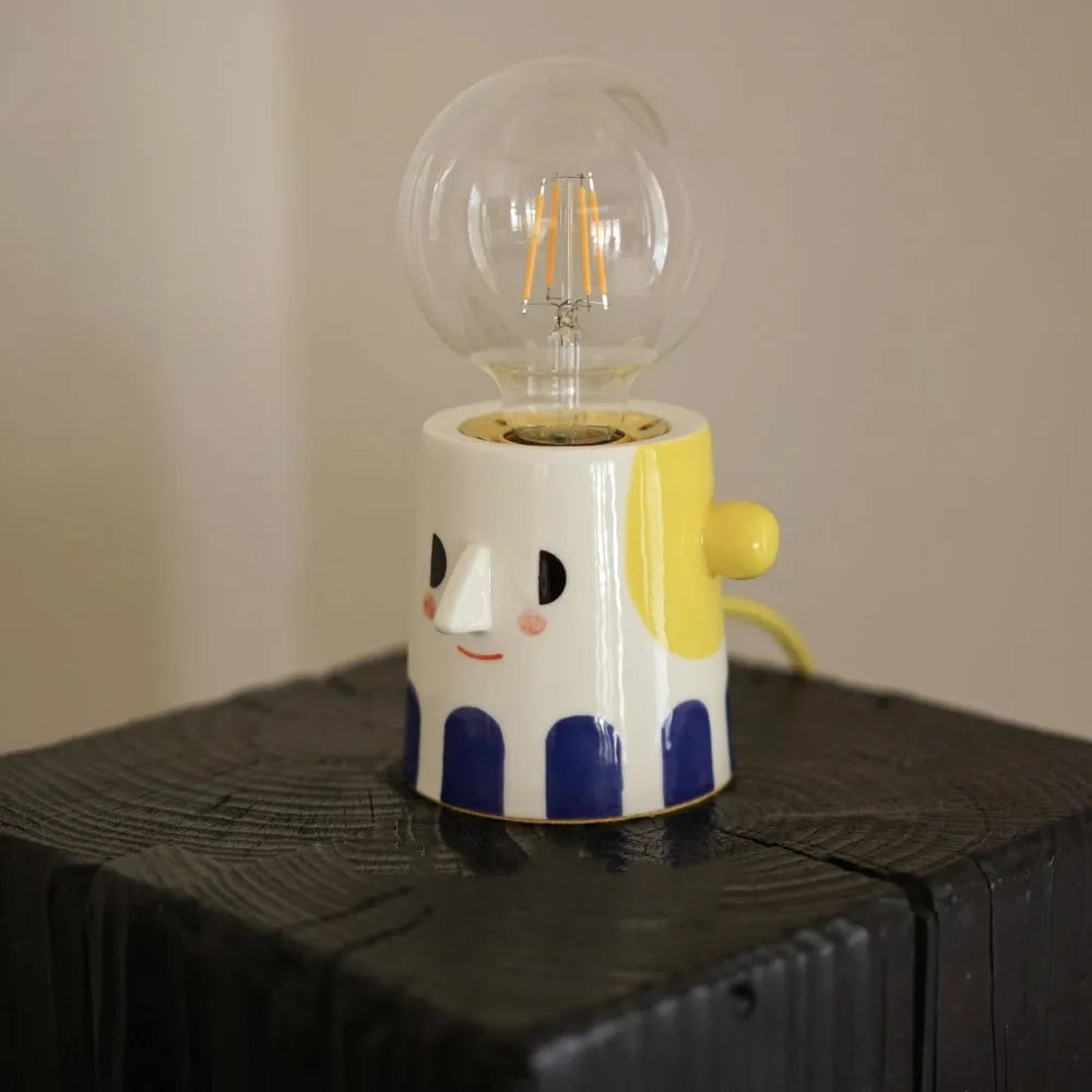 Handmade ceramic bedside lamp with ball headlight colour design on a table.