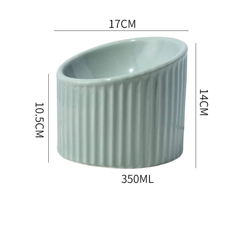 Ceramic elevated cat bowl in light green, showing its tilted, round shape and raised design on a table.