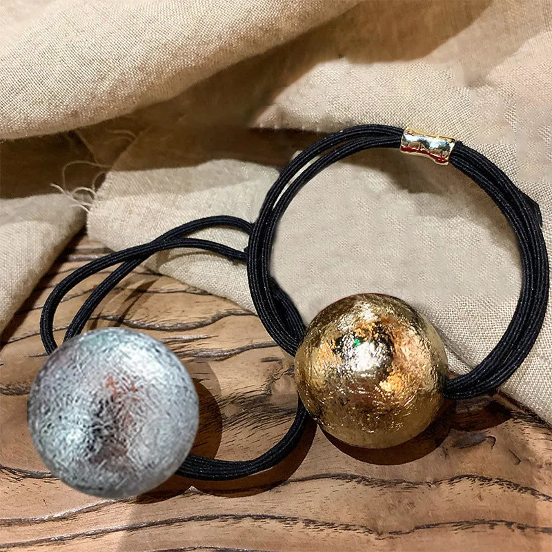 Resin hair band with electroplated gold finish, round head rope style, on a plain background