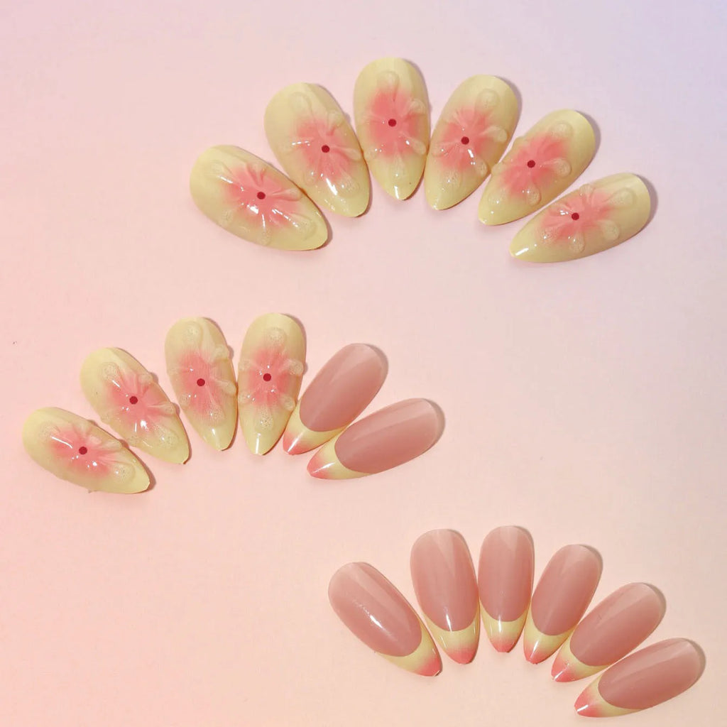 Set of fake nails with colourful 3D cartoon flower designs, jelly glue, and a nail file on a pink background.