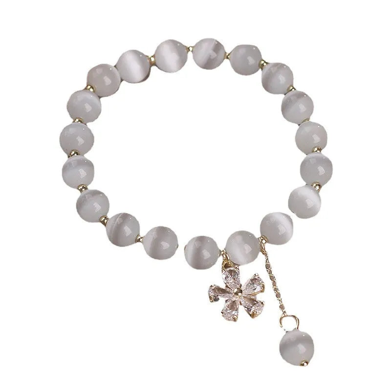 White cat's eye stone women's bracelet with flower tassel and safety buckle.