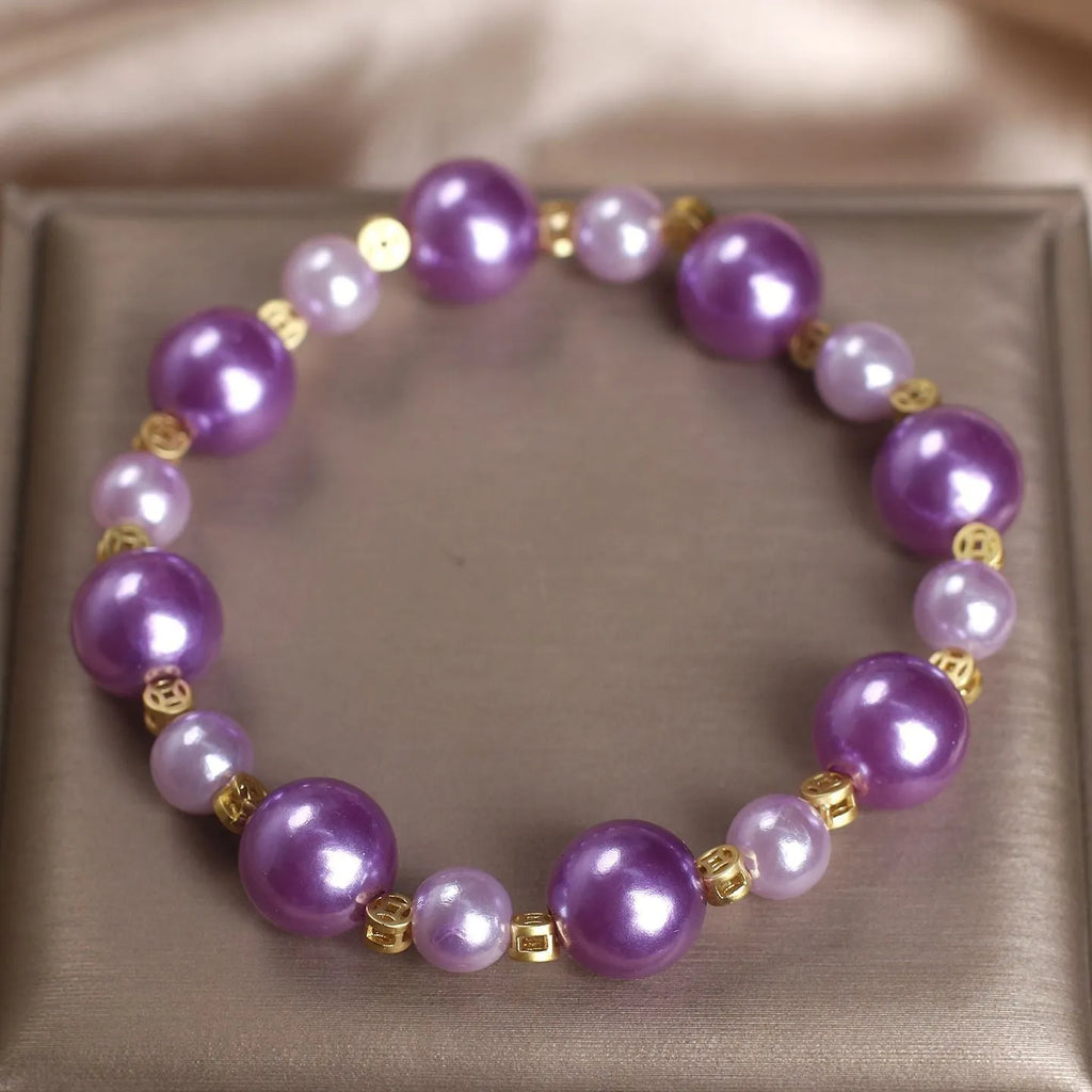 Purple shell pearl bracelet with letter coin accent on white background
