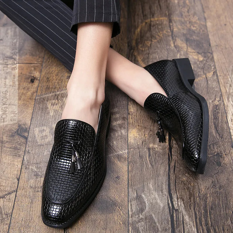 Men's black pointed slip-on leather shoes with a tassel detail on the low-top upper.
