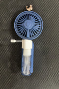Compact plastic USB desk fan in apricot colour on a wooden desk surface.