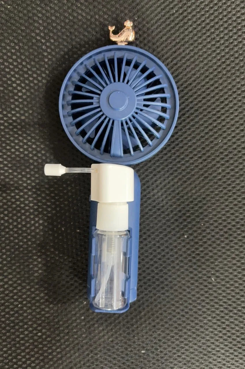 Compact plastic USB desk fan in apricot colour on a wooden desk surface.
