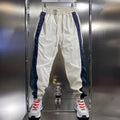Men's loose fit contrast stripe jogger sports pants in black, showing drawstring waist and tapered leg
