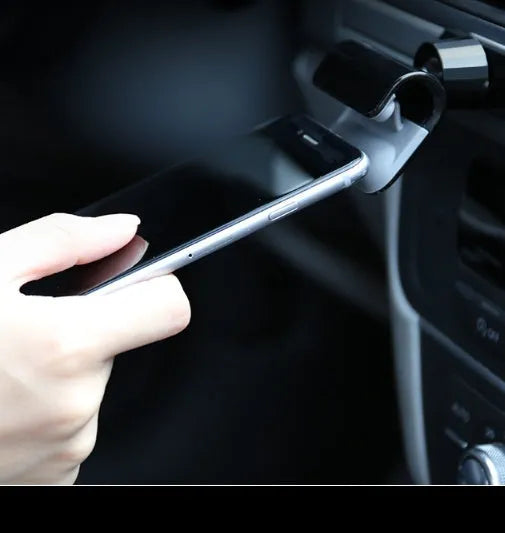 Black gravity car phone holder with 360-degree rotation mounted on a car dashboard.