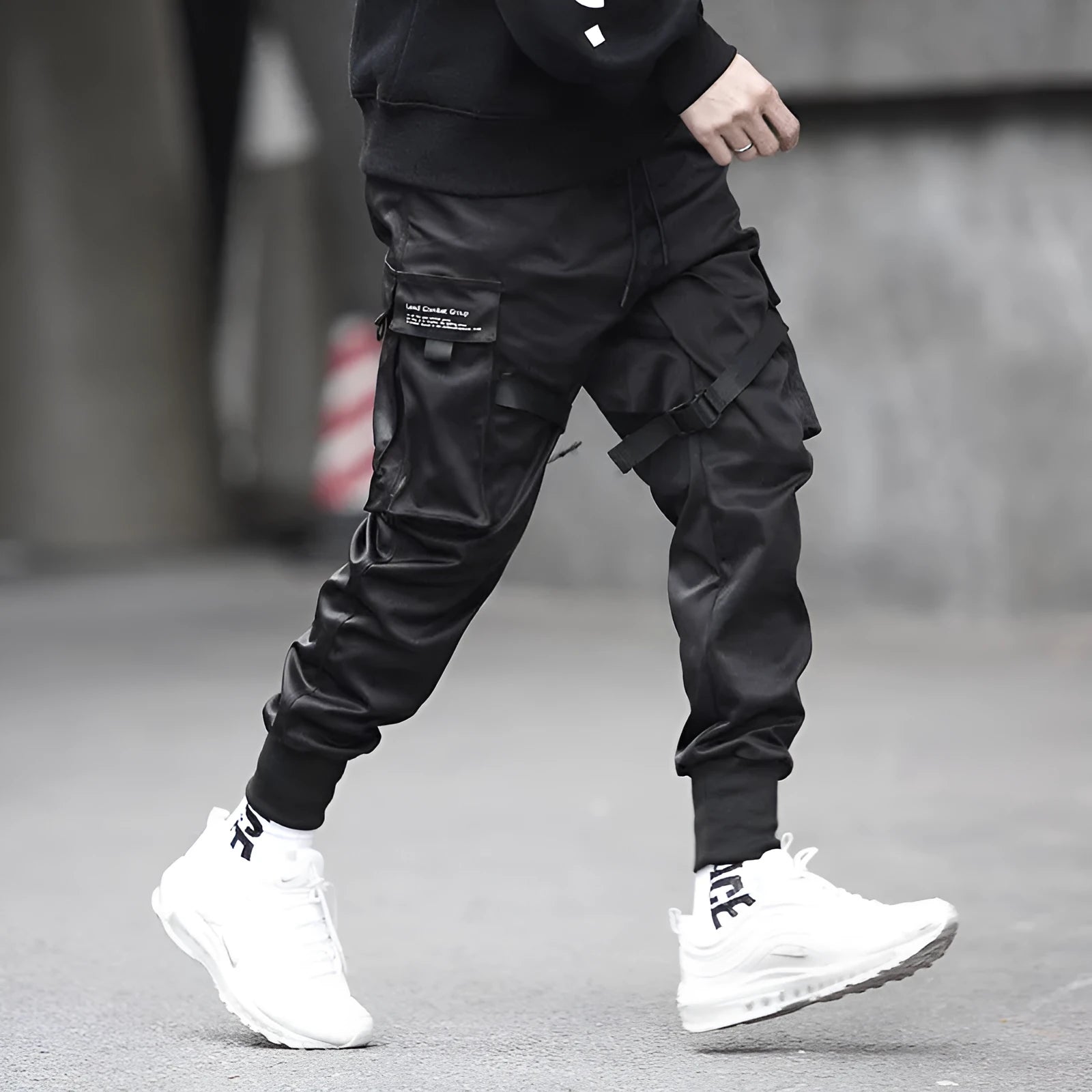Black cotton overalls with tapered leg and small foot opening on plain background