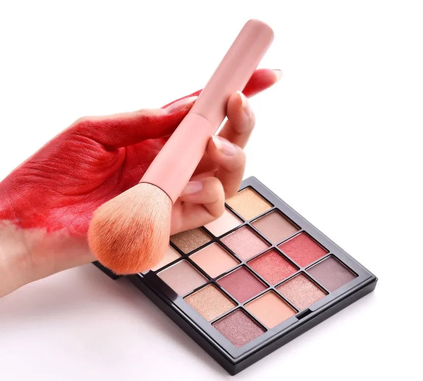 Ten cosmetic makeup brushes with wooden handles arranged showing various brush head shapes and sizes