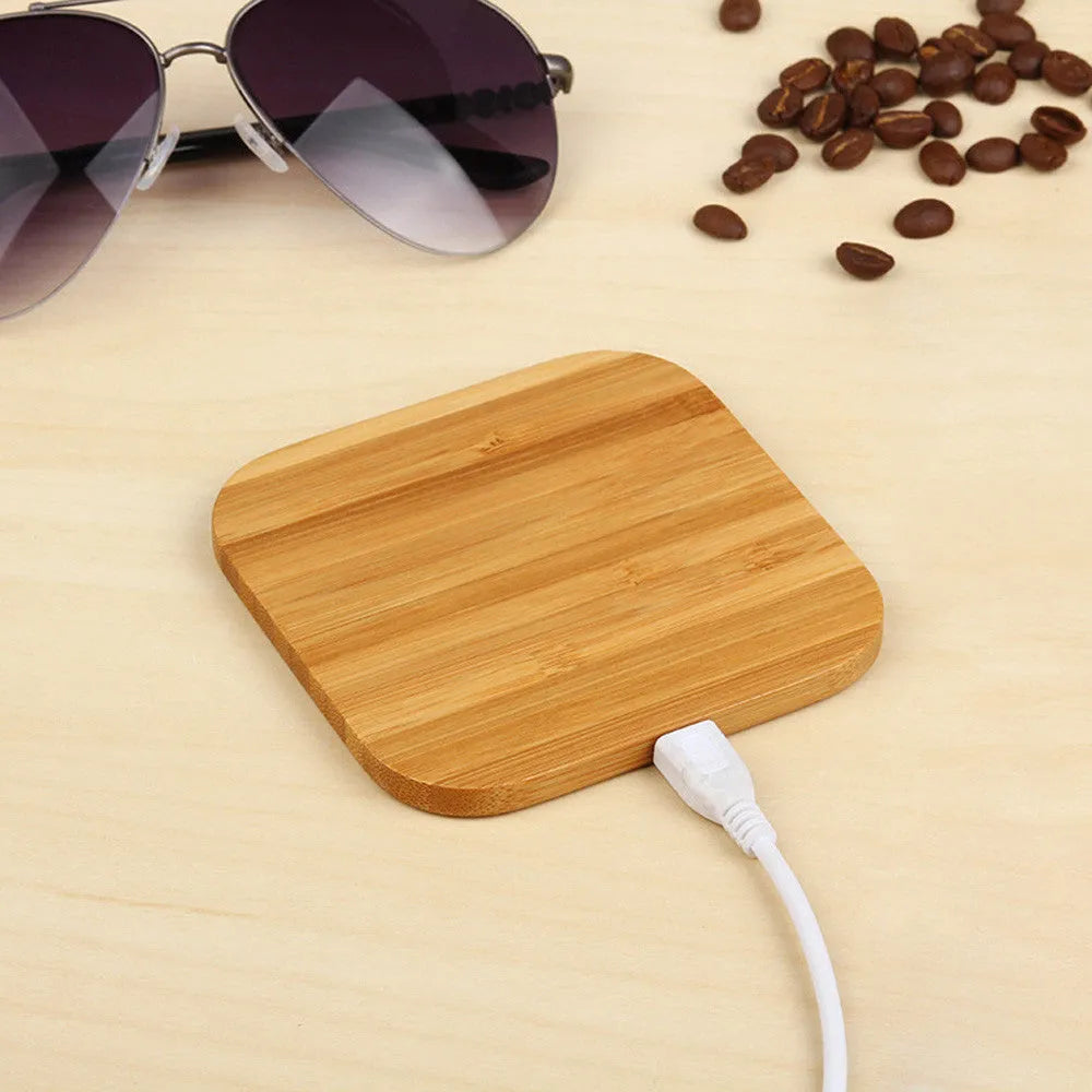 Square wooden bamboo 5W QI wireless charging pad for smartphones on a desk.