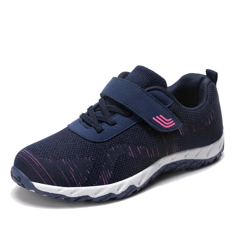 Women's grey purple wedge shoe with Velcro strap and mesh upper on a solid colour background.