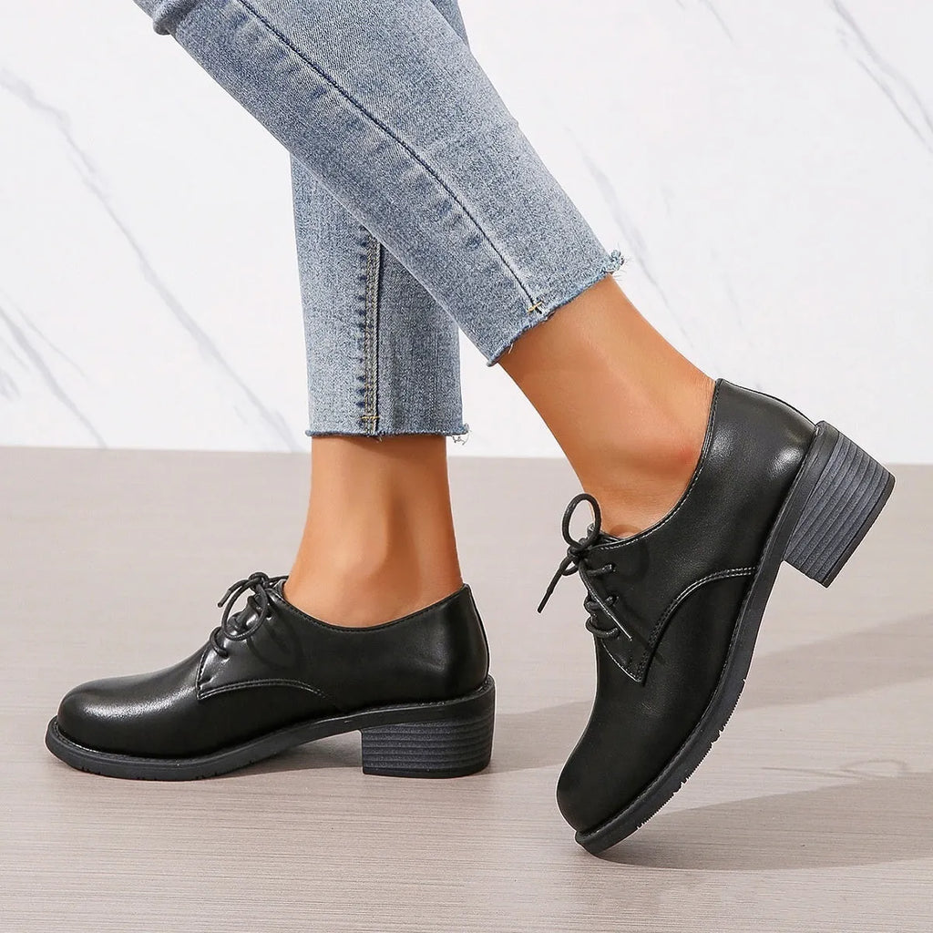 Black women's low-top work shoes with a chunky mid heel and soft rubber sole.