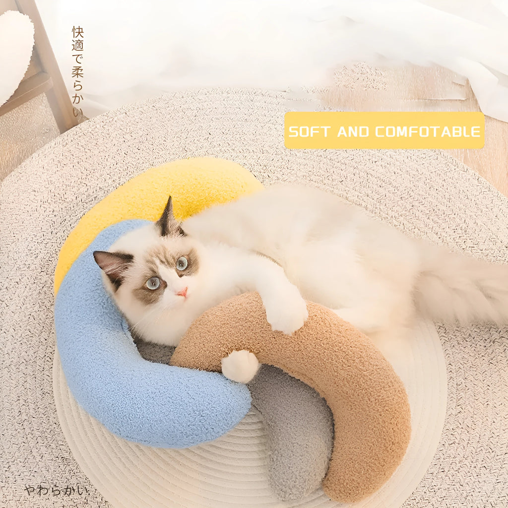 Blue U-shaped cat pillow with an adjustable fabric collar on a grey sofa