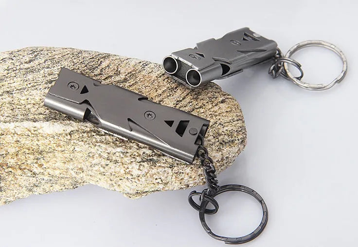 Keychain whistle in black with metal lanyard ring on a plain background