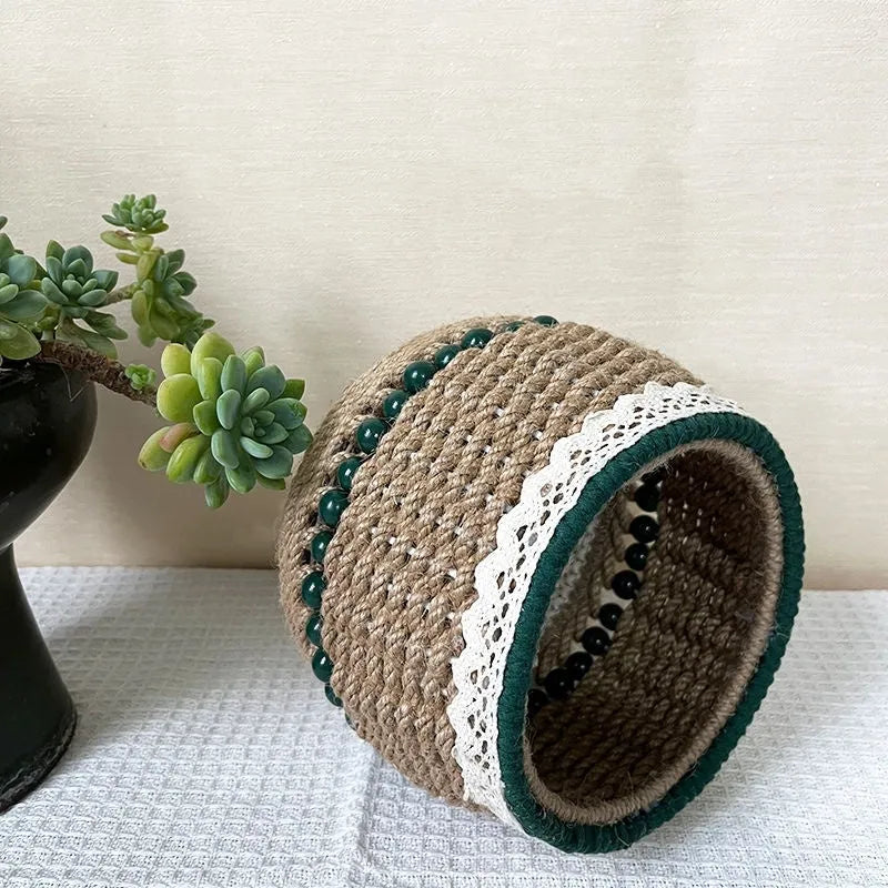 Rattan hand woven cylinder storage basket in green on desktop holding snacks and keys