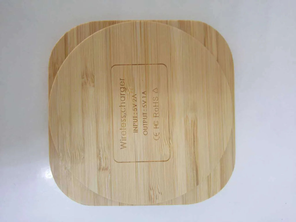 Square wooden bamboo 5W QI wireless charging pad for smartphones on a desk.