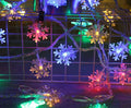 Battery powered LED snowflake string lights with star decorations lit on a dark background