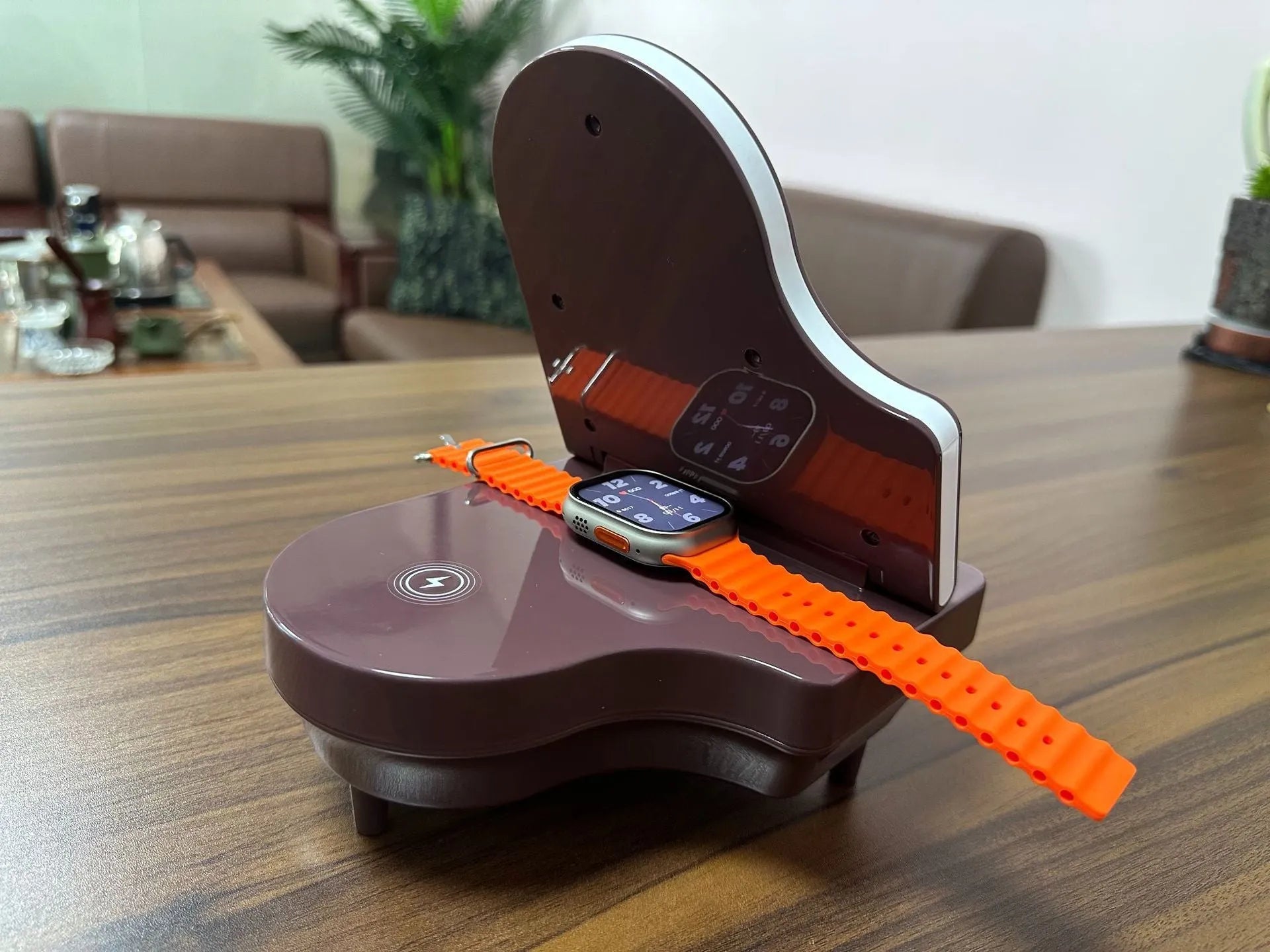 Black multi-function Bluetooth speaker with wireless charger and phone holder on a desk