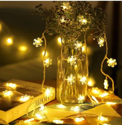Battery powered LED snowflake string lights with star decorations lit on a dark background