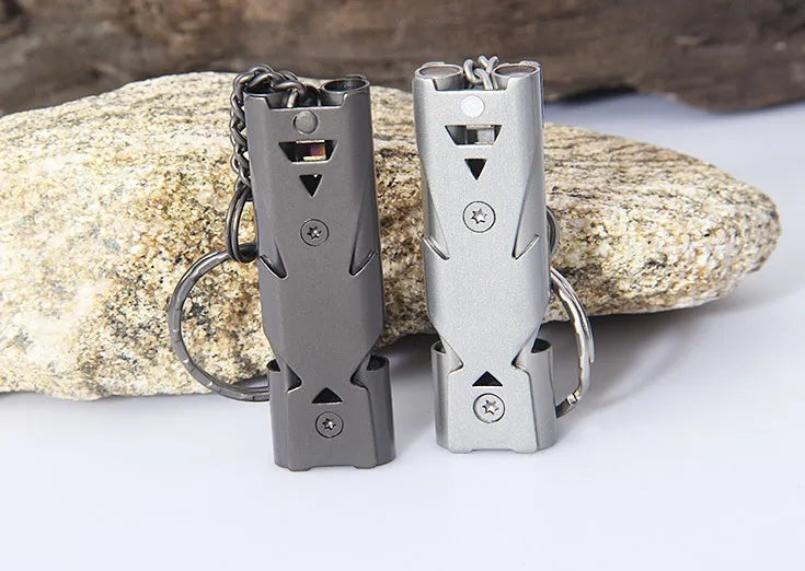 Keychain whistle in black with metal lanyard ring on a plain background