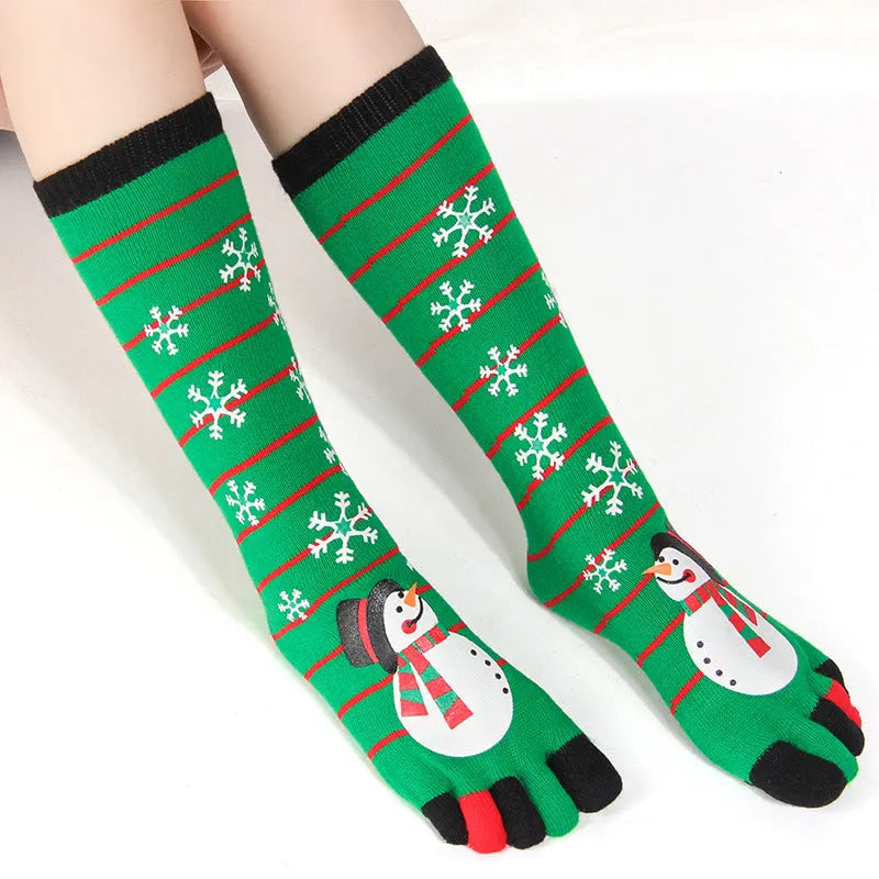 Christmas five finger socks with cartoon patterns in black, green, and white on a neutral background