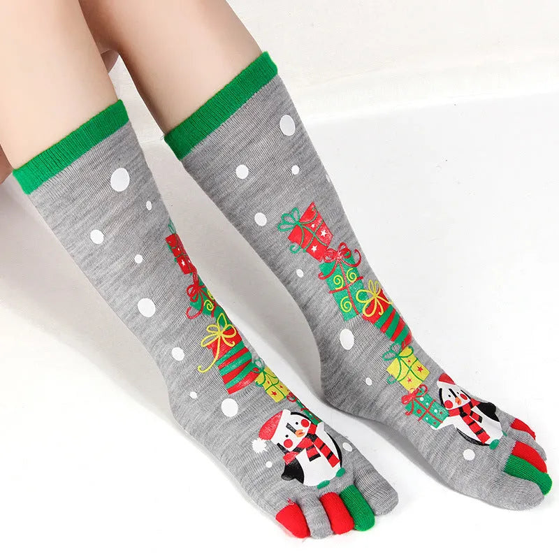 Christmas five finger socks with cartoon patterns in black, green, and white on a neutral background