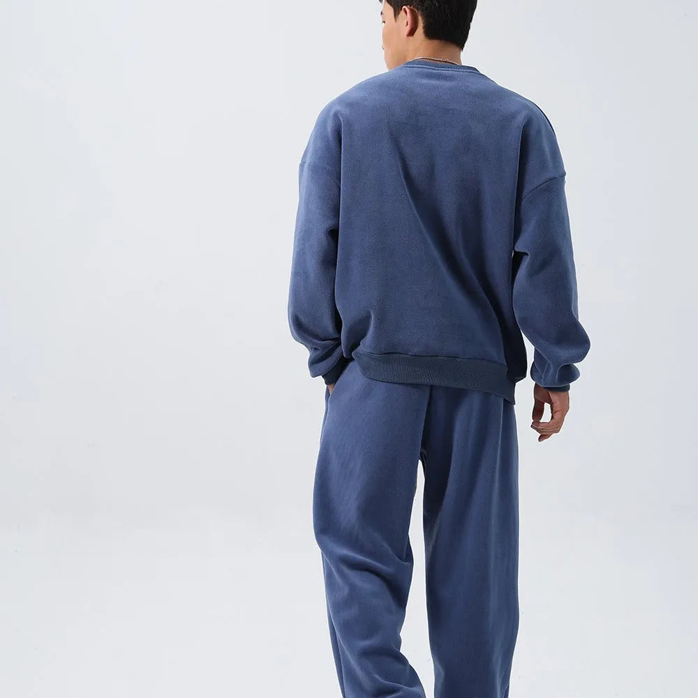 Men's black polar fleece sports suit with loose long sleeve coat and matching trousers on a hanger.