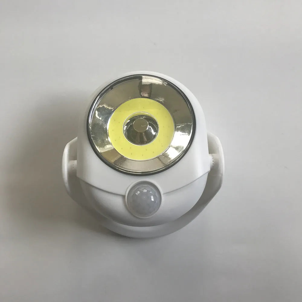 White Atomic Angel induction desk lamp with compact ABS plastic housing on a desk.