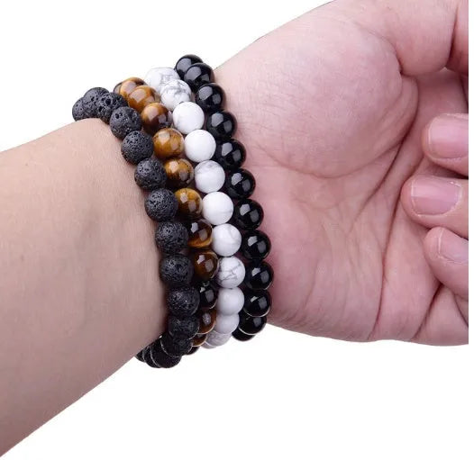 Black onyx geometric bead bracelet with elastic cord on a wrist.