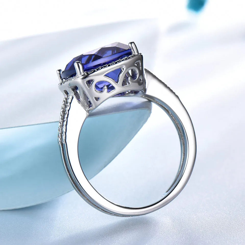 Women's 925 Sterling Silver ring with a blue Tanzanite stone, shown on a finger.