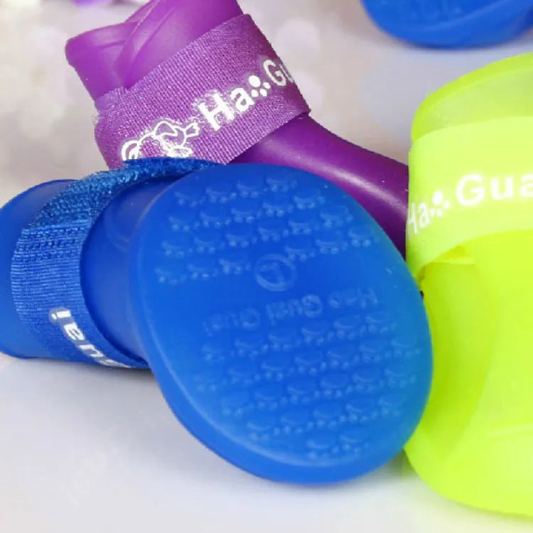 Soft silicone pet rain boots in royal blue on a wet pavement, non-slip sole visible