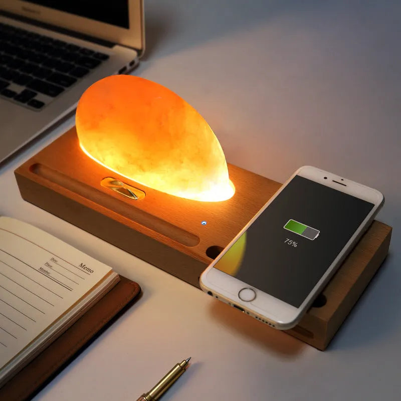 Wooden base Himalayan salt lamp with wireless phone charging pad on top showing warm white glow.