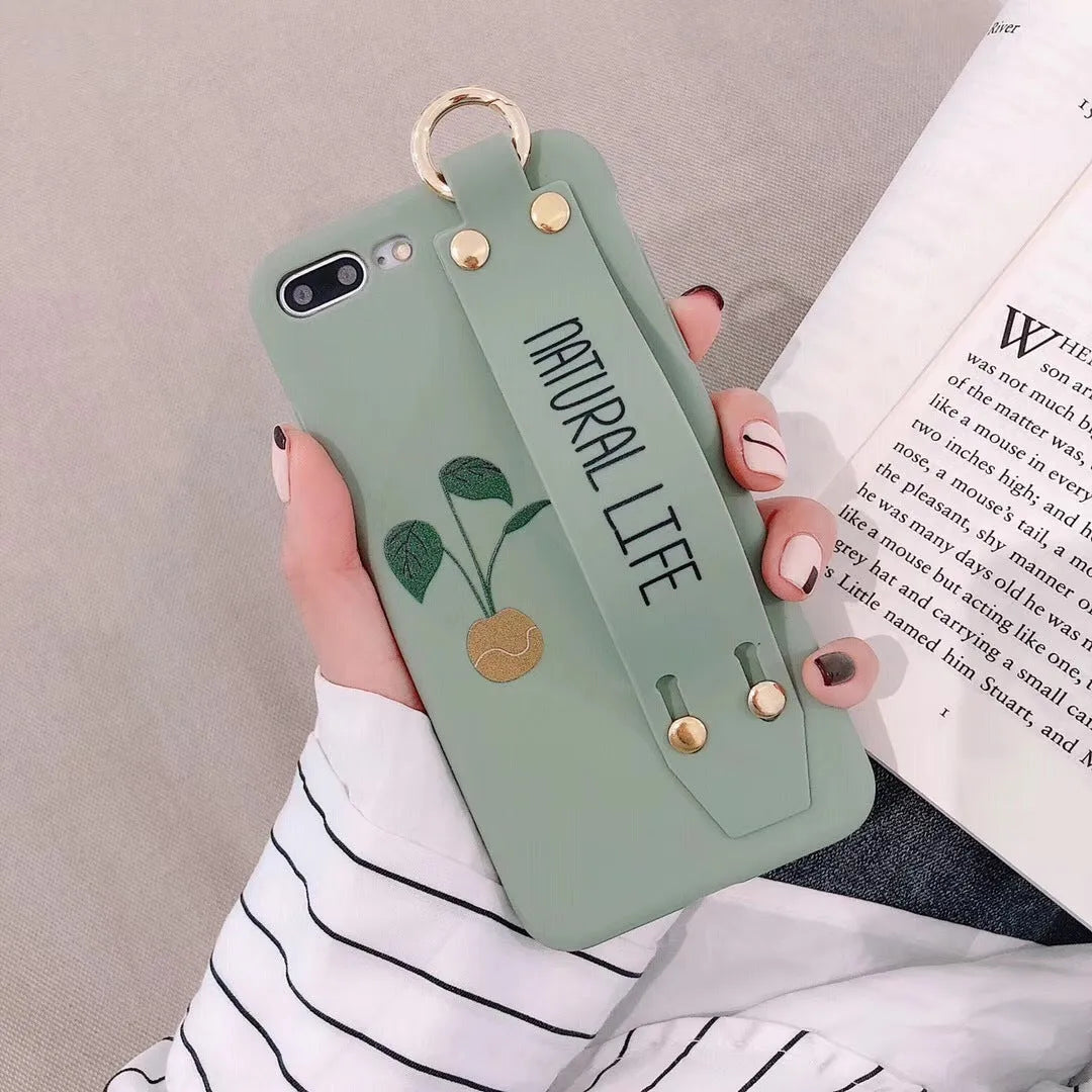 Green graffiti design iPhone case with a black detachable wrist strap looped around a hand.