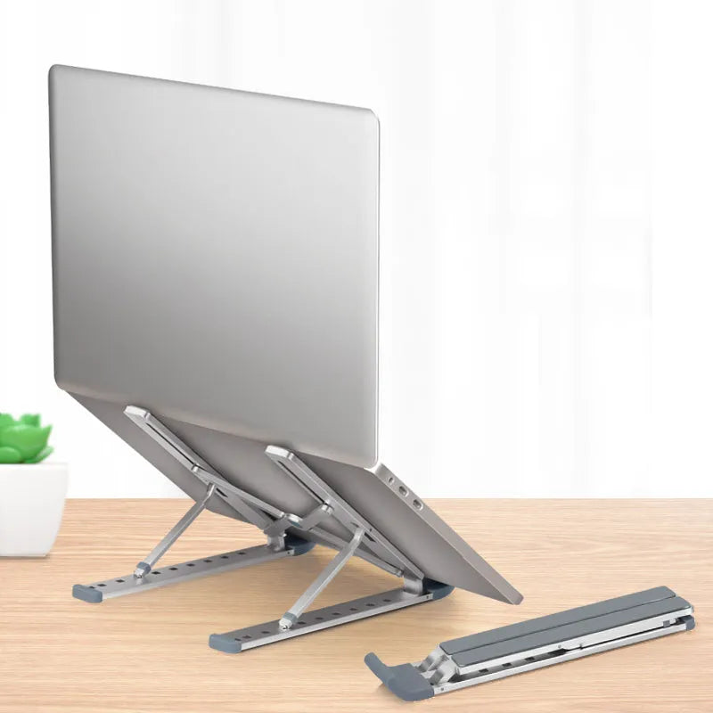 Adjustable folding laptop stand in silver, open on desk with laptop, showing hollow bottom and non-slip silicone pads