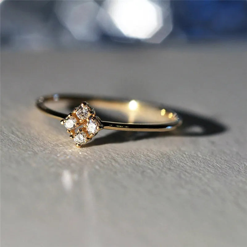Four heart-shaped motif gold rings with zircon stones set on a dark surface