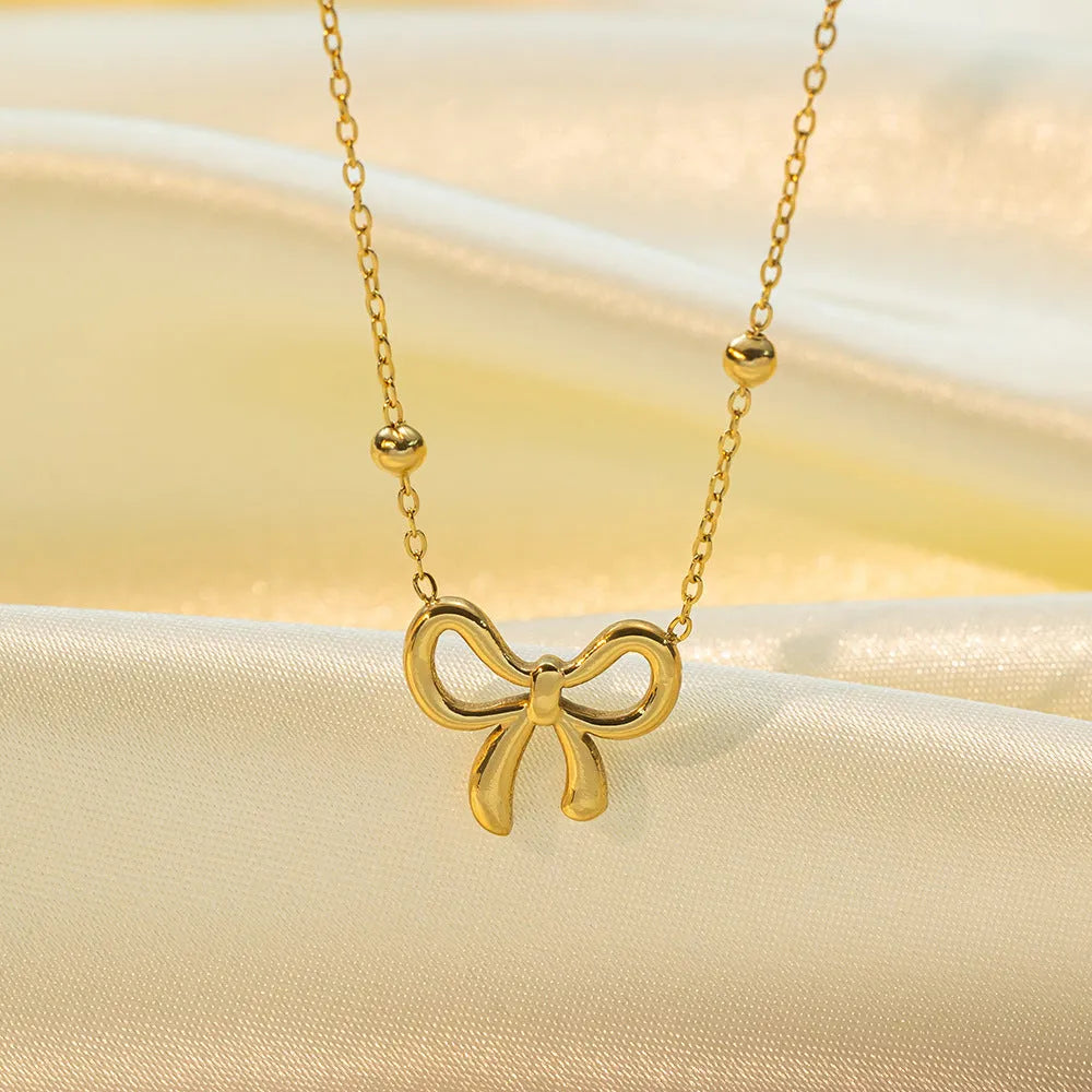 Gold-coloured titanium steel necklace with bow design and cross chain construction